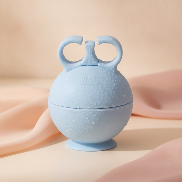 Close-up of an ice facial roller with condensation on its silicone core, resting on a cream surface with soft peach fabric.